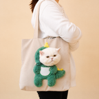 Sac de transport chat tête dehors Pawkaboo — costume dinosaure vert sur sac crème, chat blanc porté à l'épaule